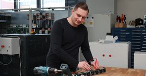 Niklas Thom, ein großer Mann, der den Strom an einer Fahrradbatterie misst.