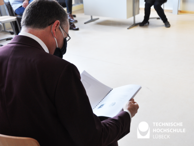 Konzernchef Stefan Dräger wirft einen Blick in die Projektarbeit, die von den Schülern Veit Ahlers, Marvin Goy und Michel Adam über die Wetterstation der Baltic Schule verfasst wurde. Foto: TH Lübeck