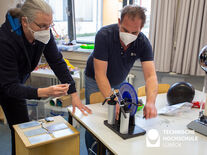 Auf dem Bild sieht man links Volker Geist und rechts Jochem Bohnet wie sie eine Blitzmaschine ausprobieren