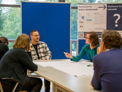 Vier Personen sitzen an einem Tisch und diskutieren