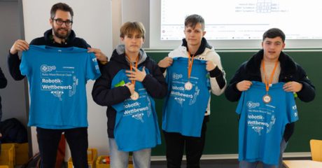 Auf dem Bild sieht man vier Personen mit blauen T-Shirts vor sich