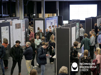 Viele Menschen gehen um Ausstellungswände und schauen sich Plakate an 