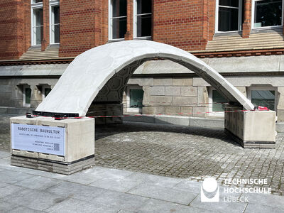 Betonpavillon steht auf drei Stützen auf einem Vorplatz