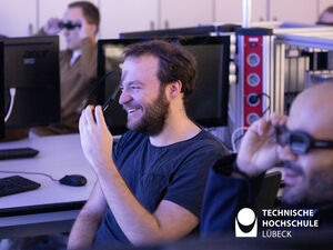 Lachende Studierende sitzen verteilt in einem Labor der Hochschule und nehmen sich 3D-Brillen von den Augen.