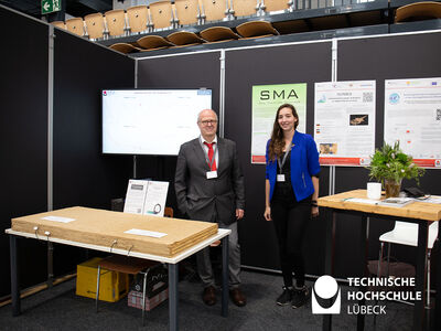 Prof. Külls und seine Mitarbeiterin präsentieren auf ihrem Stand einen Messaufbau mit Lehmbauplatten. Foto: TH Lübeck