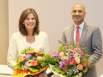 Mann und Frau stehen nebeneinander und halten jeweils einen Blumenstrauß