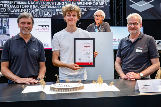 Platz 2 Drei Personen nebeneinander und eine hält Urkunde