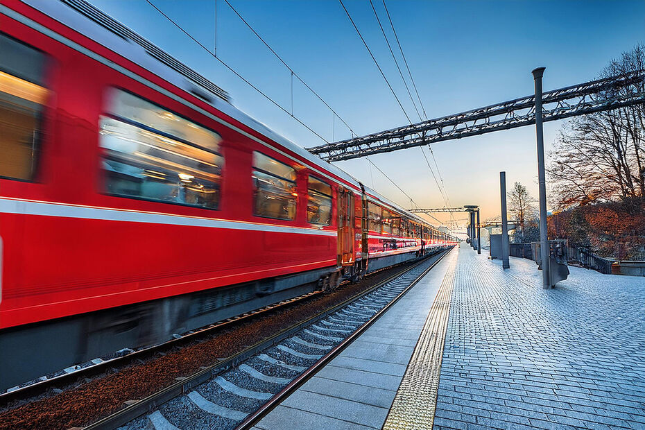 Ein roter Regionalexpress der Deutschen Bahn fährt durch einen Bahnhof