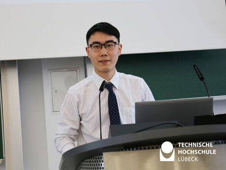 Der IT-Absolvent Rui-Song spricht auf Englisch und Deutsch zu seinen Kommilitonen und den Gästen. Foto: TH Lübeck 