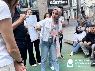 Studentin zeigt auf Karte und Studierende gucken zu ihr