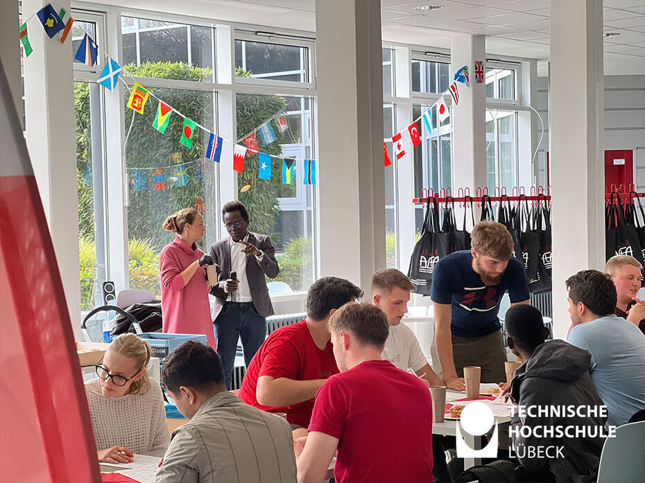 Die international Studierende sitzen im beschmückten Atrium und spielen Bingo