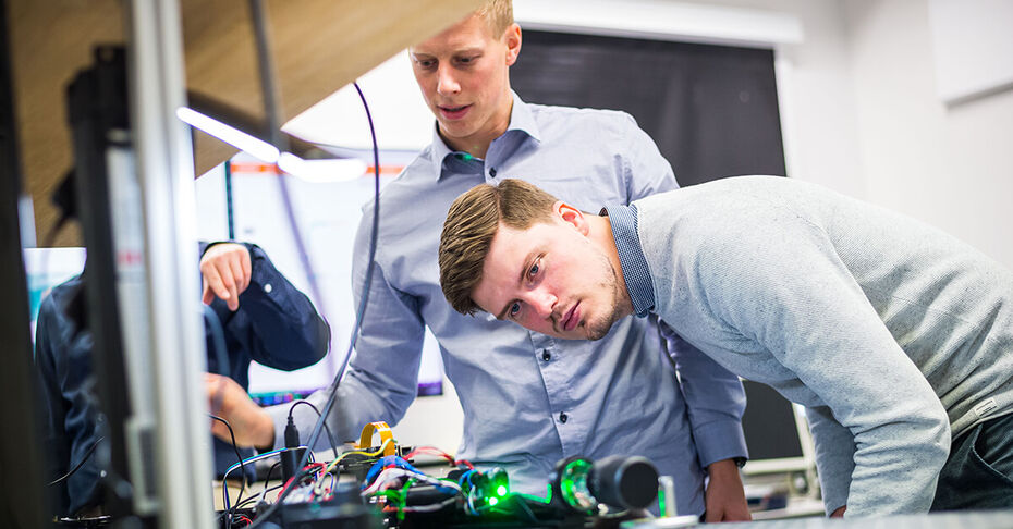 Zwei Ingenieure der TH Lübeck analysieren technische Geräte und arbeiten an innovativen Projekten wie KI-gestützten Diagnoseverfahren für die Medizin.