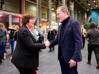 Mann begrüßt mit Handschlag eine Frau