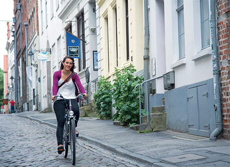 Eine Studentin der TH Lübeck fährt auf einem Fahrrad durch die historische Innenstadt der Hansestadt Lübeck